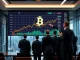 Bitcoin News Today: A company executive observing a rising Bitcoin chart on a large screen, symbolizing strategic corporate Bitcoin holdings and institutional adoption.