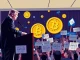 Pro-crypto candidate James Walkinshaw speaking at a rally with cryptocurrency symbols in the background