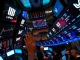 Screens on a trading floor displaying mixed performance data for the US stock market, including S&P 500, NASDAQ, and Dow Jones, reflecting current investor sentiment.