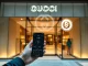 Gucci store embracing crypto payments, symbolizing luxury brand crypto adoption with ETH and DOGE logos.