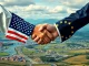 A symbolic handshake between US and EU flags, representing the landmark US-EU trade deal that averts a tariff crisis.