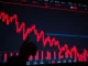 A grim red downward arrow over a blurred background of stock market tickers, symbolizing the US stocks lower trend and overall stock market decline.