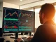 Financial analyst monitors Bitcoin and cryptocurrency price charts on a trading workstation.