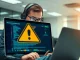 Cybersecurity analyst investigating Coinbase Commerce seed phrase security alert on laptop