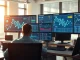 Analyst reviewing Quant blockchain network data and QNT price charts on trading desk monitors