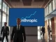 Anthropic fundraise news: AI company's logo displayed in modern office lobby with upward trend graph.