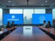 Business professionals in a boardroom with Anthropic and OpenAI logos on screens