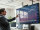 Financial analyst reviewing AVAX price chart on large digital display in modern office