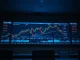 Cryptocurrency price charts displayed on multiple screens in a professional trading environment