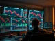 Trading desk monitors showing Bitcoin futures charts and market data with cautious sentiment