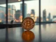 Bitcoin price prediction for 2026 and 2030: A Bitcoin coin on a table with financial charts in the background.