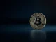 Bitcoin coin on dark reflective surface with dramatic lighting, representing market resistance analysis.