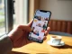 Bumble app on a smartphone screen with new AI features replacing the swipe gesture in a cafe setting