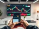 Digital display showing Bitcoin price chart with a smartphone on a desk in a professional newsroom setting.