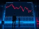 ETH/BTC price chart showing a sustained downtrend on a trading floor screen.