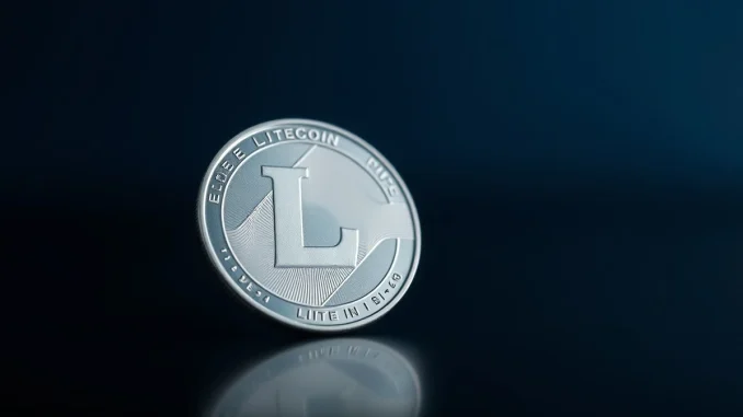 Silver Litecoin coin on dark reflective surface with soft lighting
