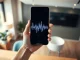 Smartphone displaying an AI voice interface with waveform graphics in a professional office setting