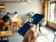 Hand holding smartphone displaying stablecoin payment interface with holographic crypto symbol