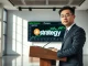 Strategy CEO Phong Le speaking at a press conference with Bitcoin charts in background