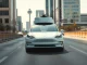 A Tesla robotaxi driving autonomously with empty front seats on a Dallas street.