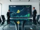 Boardroom meeting with Bitcoin chart and three business executives discussing merger deal
