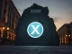 XRP token icon blocked by a stone wall marked $1.40, representing price resistance despite high sentiment.