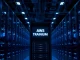 AWS data center server rack with glowing Trainium AI chip badge in blue-lit corridor