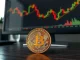 Bitcoin coin on desk with financial charts in background representing market analysis