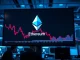 Ethereum price chart showing decline on a trading screen in a modern office