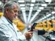 Senior automotive engineer inspecting a vehicle part on a factory floor at a Ford assembly plant
