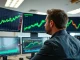 Financial analyst reviewing Bitcoin price charts on multiple monitors in a modern office