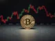 Bitcoin coin on a dark surface with blurred stock charts in background