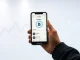 Person holding smartphone showing Kraken app with AI trading features
