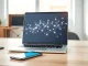 Laptop displaying an AI agent interface with a smartphone nearby in a bright office setting