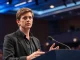 Sam Altman speaking at a tech conference with a serious expression