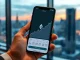 Smartphone displaying Robinhood app with Ethereum price chart surging upward in a professional office setting.