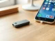 Gray NFC key from Autonomous resting on a wooden desk beside a smartphone