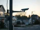 A pole-mounted surveillance camera overlooking a residential street at dusk, representing Flock Safety's technology.