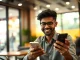 Young Indian professional using a smartphone with a payment confirmation screen in a cafe, symbolizing rising app spending.