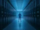 A glowing blue digital figure stands in a data center corridor, representing an AI agent.