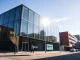 OpenAI headquarters in San Francisco, with employees entering the building on a sunny afternoon.