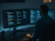 Cybersecurity researcher working on a computer with code on screens, representing OpenAI's Trusted Access for Cyber program access issue.