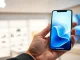 A hand holding an iPhone displaying a glowing AI assistant interface, representing the future Siri AI upgrade.