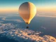 Weather balloon with sensor package ascending above clouds at sunrise