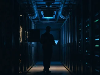 Technician in a server room checking a rack during an emergency software patch